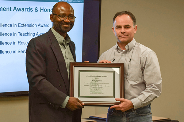 Dr. Mark Skidmore with AFRE Chair Titus Awokuse receiving his award