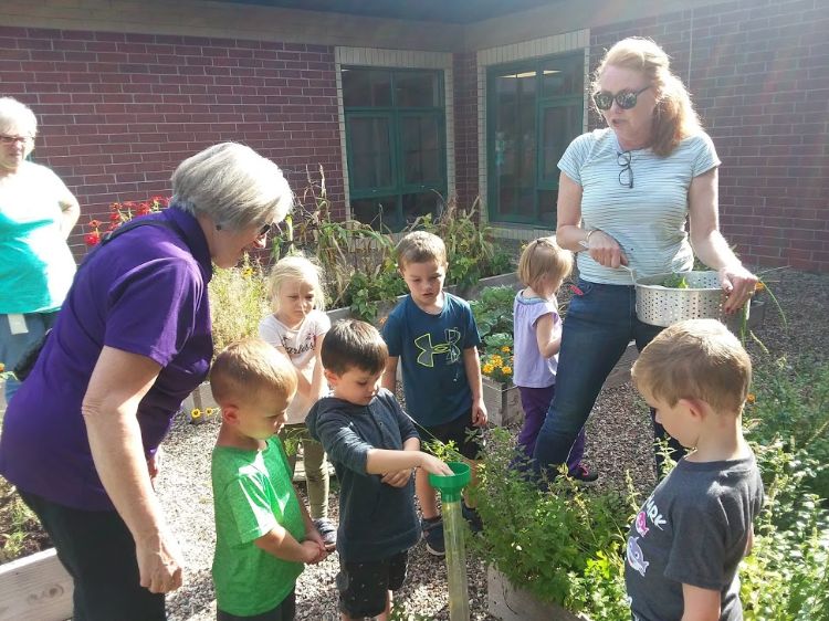 Students and Extension Master Gardeners examine a rain gauge
