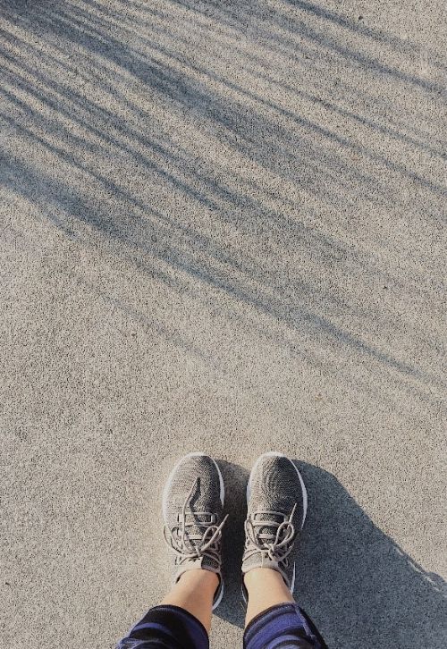 A person's legs with grey sneakers.