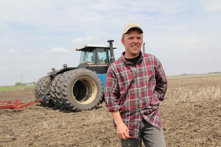 A man standing in front of a tractor in a field.