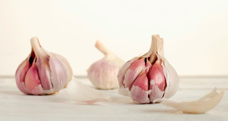 Three complete heads of garlic rest on a cutting board.