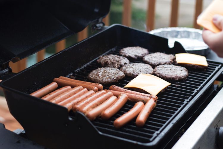 Hot dogs and burgers cooking on a grill.