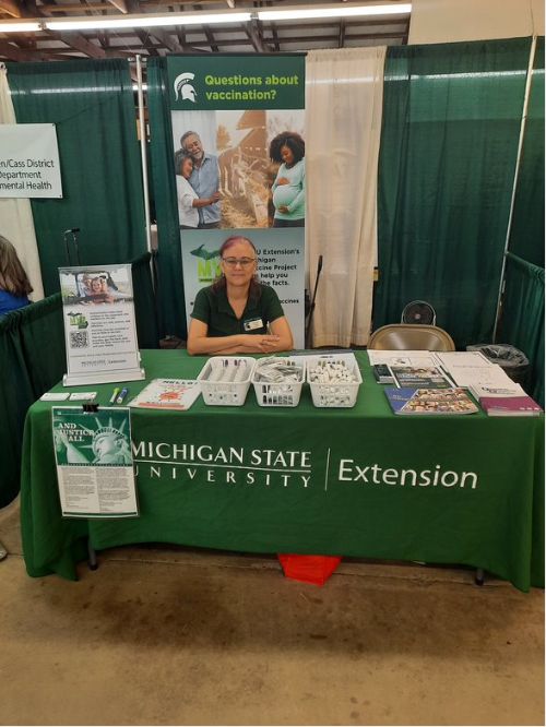 A photo of Michigan Vaccine Project program instructor Corinne Lopez tabling at the Van Buren County Youth Fair Day.