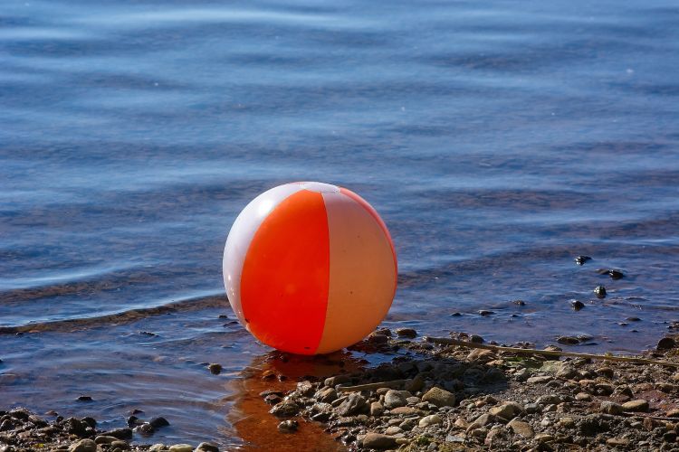 A beach ball on a rocky shore.