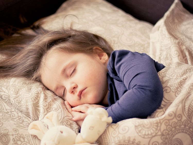 A child sleeping with a stuffed toy.