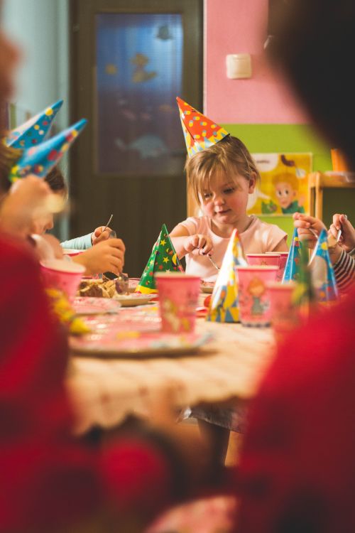 Girl celebrating her birthday in a classroom with party hat on.