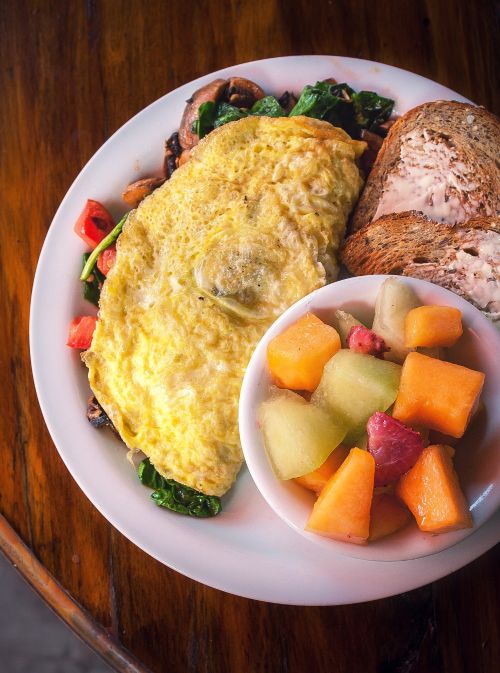 Omelet with bread and fresh fruit on a plate.