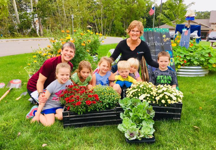 Kendra Gibson poses with a group of students in front of a garden box.