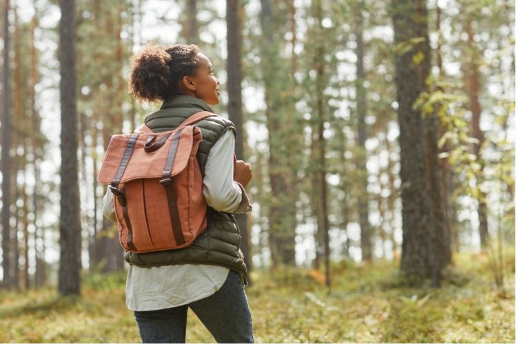 A photo of a woman wearing a backpack and hiking through the woods