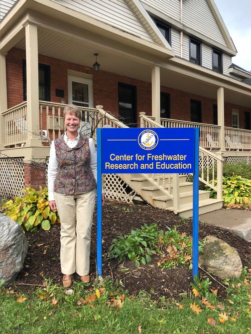 Beth Christiansen stands near a sign at Lake Superior State University that reads Center for Freshwater Research and Education. As Education and Outreach Specialist she will work with the general public, students, and educators across the state to learn of the importance of the Great Lakes waters and each individual’s unique role in protecting and preserving the larger system through their actions at the local level.