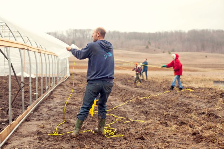 Aaron Brower (front) works with the family to build Bluestem Farm’s new hoophouse.