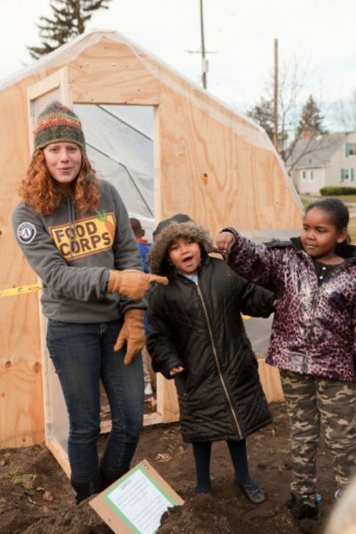 FoodCorps member Robyn Wardell pointing at a worm with two students in Flint.