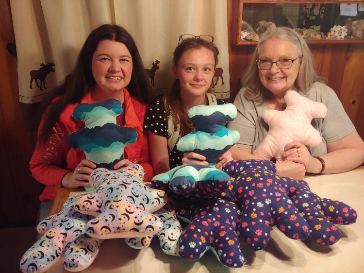 Two youth and a volunteer with the teddy bear projects they sewed.