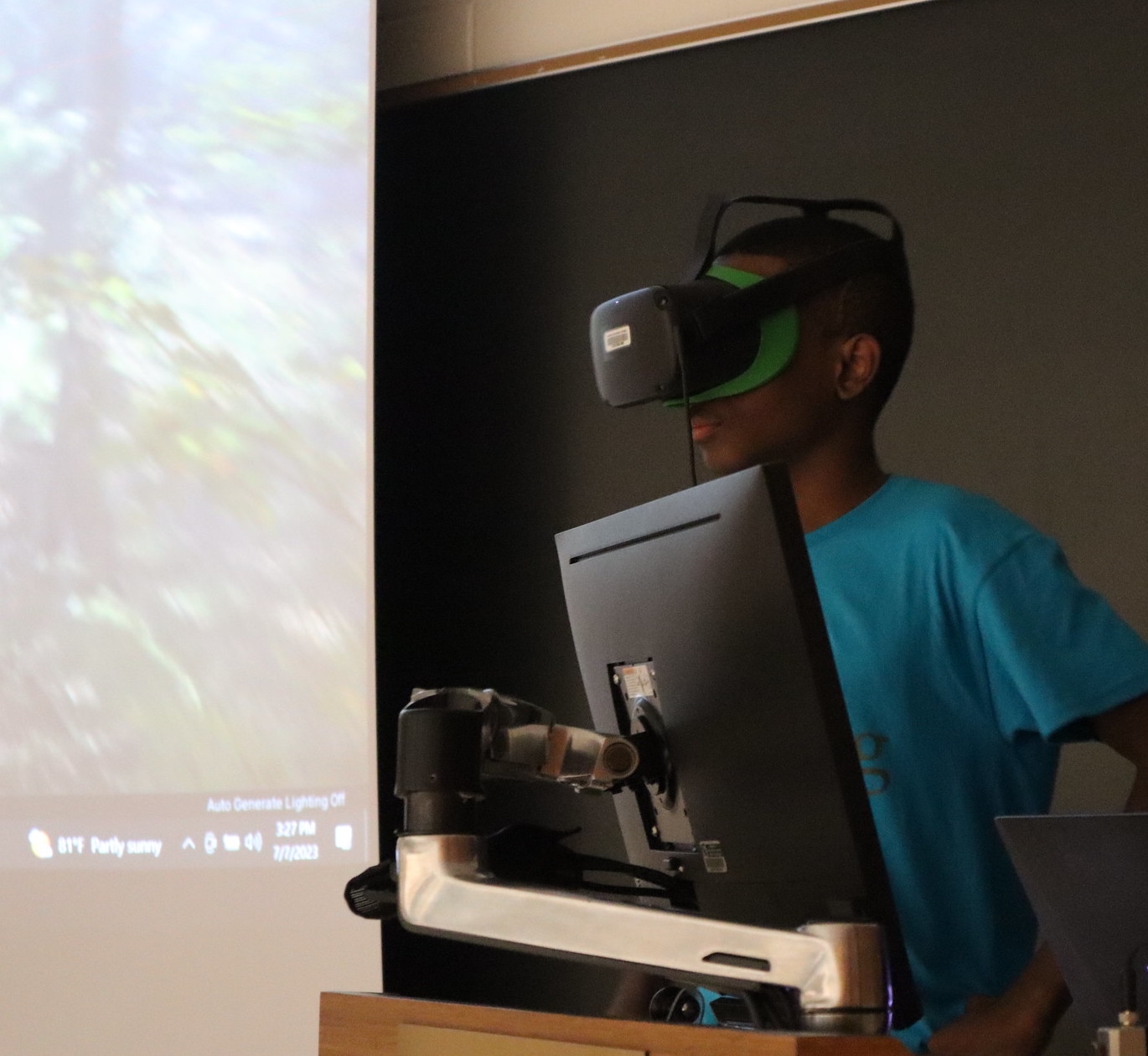 A Green Corps student using a VR headset and hand controls to explore a virtual forest developed by the Forest + Climate Visualization Partnership.
