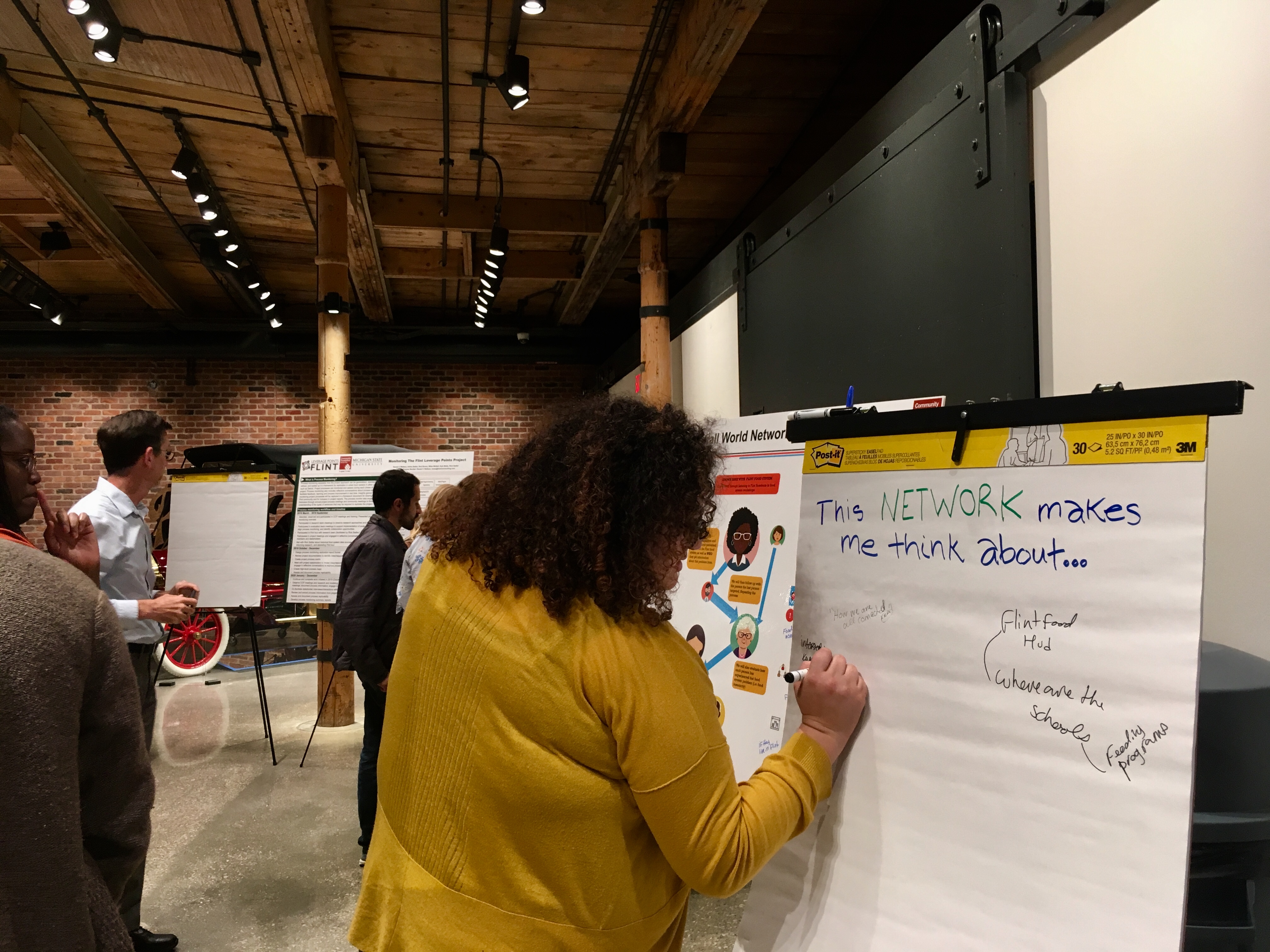 Woman writes on a flip chart at a community forum in Flint