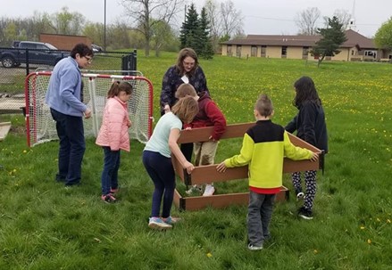 Adults and youth carry a raised garden bed