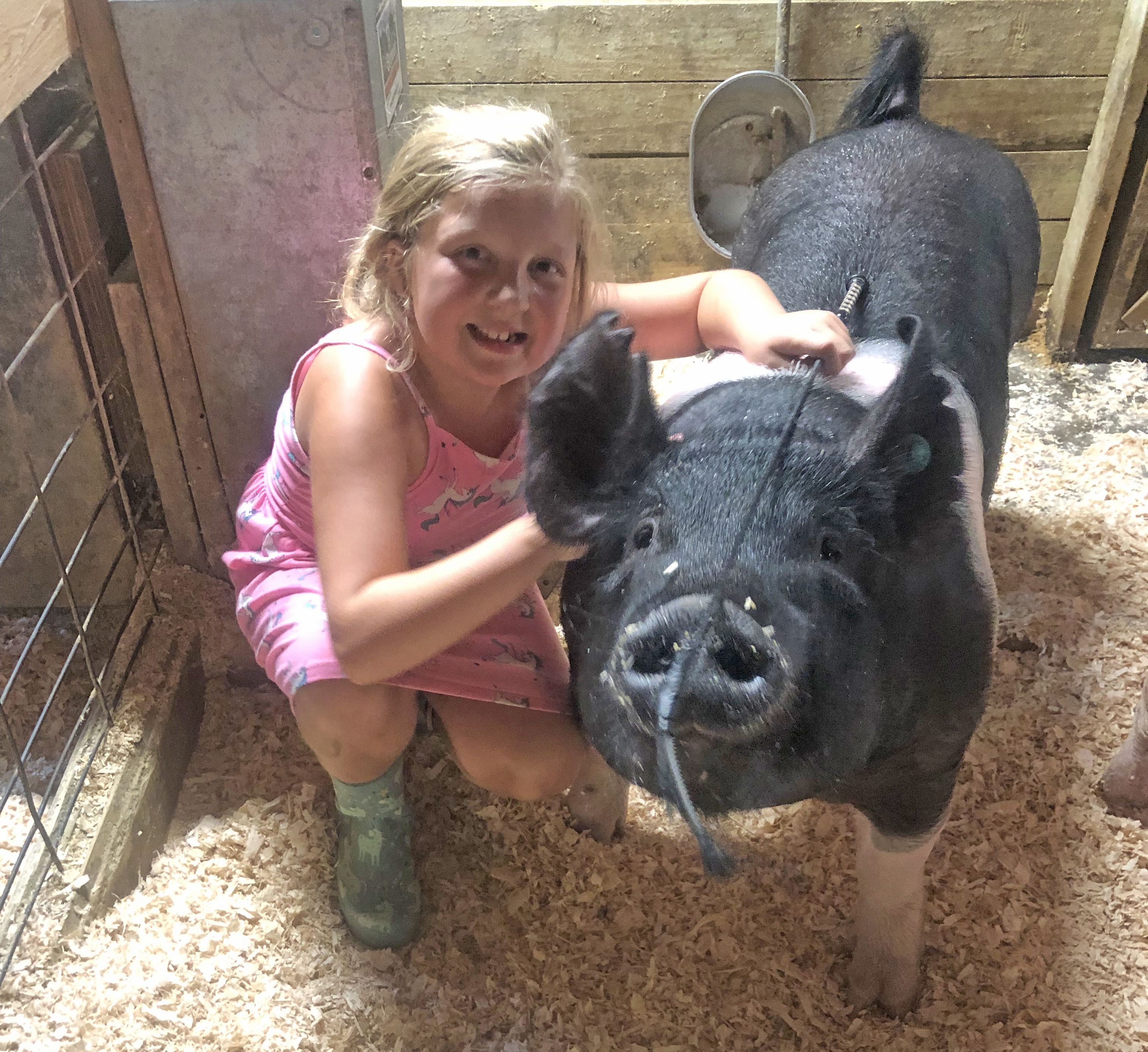 A girl posing for a picture with her pig.