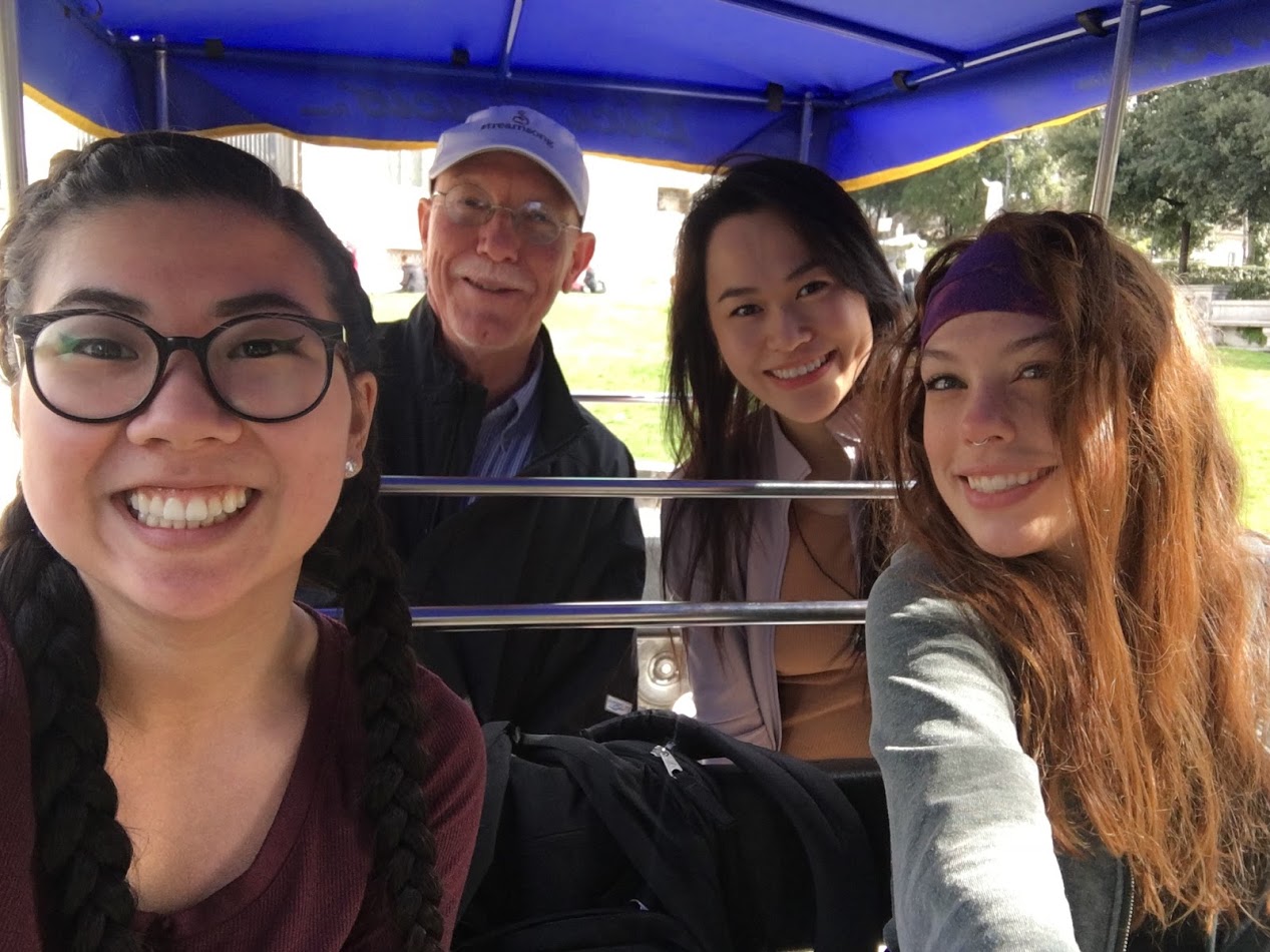 Students and faculty sitting in a pedal carriage.