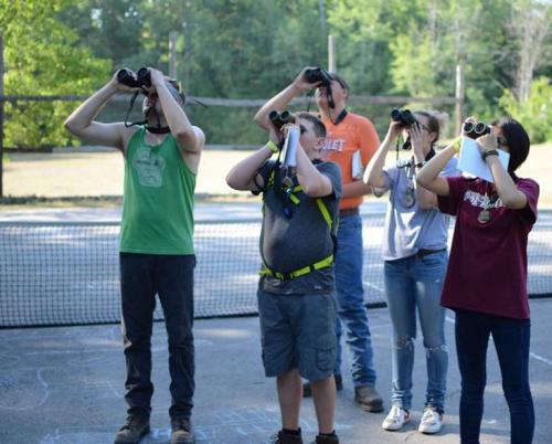 Youth look through binoculars at birds.