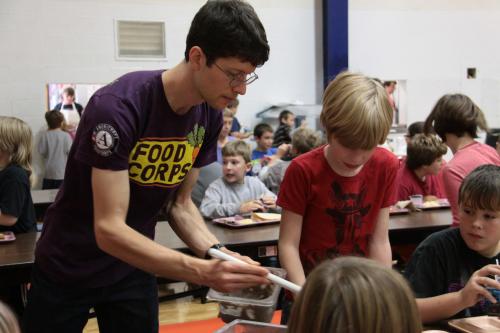 FoodCorps volunteer serves food to kids