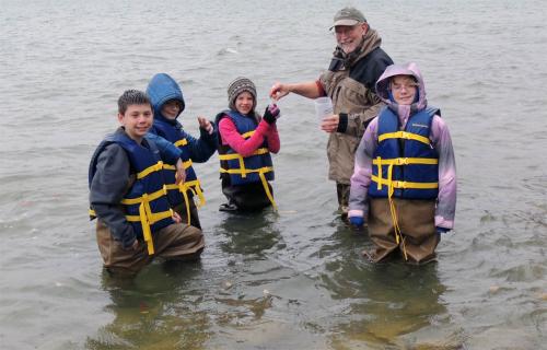 Adult volunteer with students collecting water samples image.