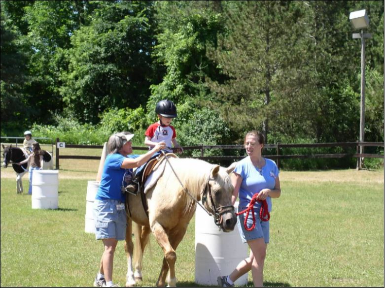 Volunteers leading a youth riding horseback.