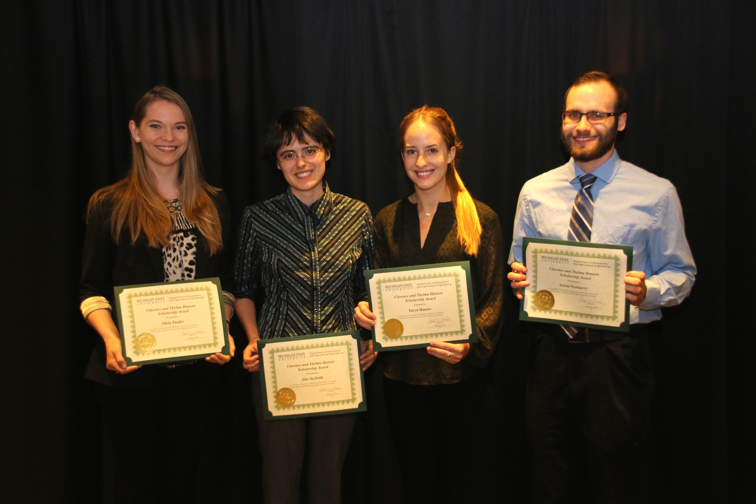 Three female students and one male student standing with award plaques