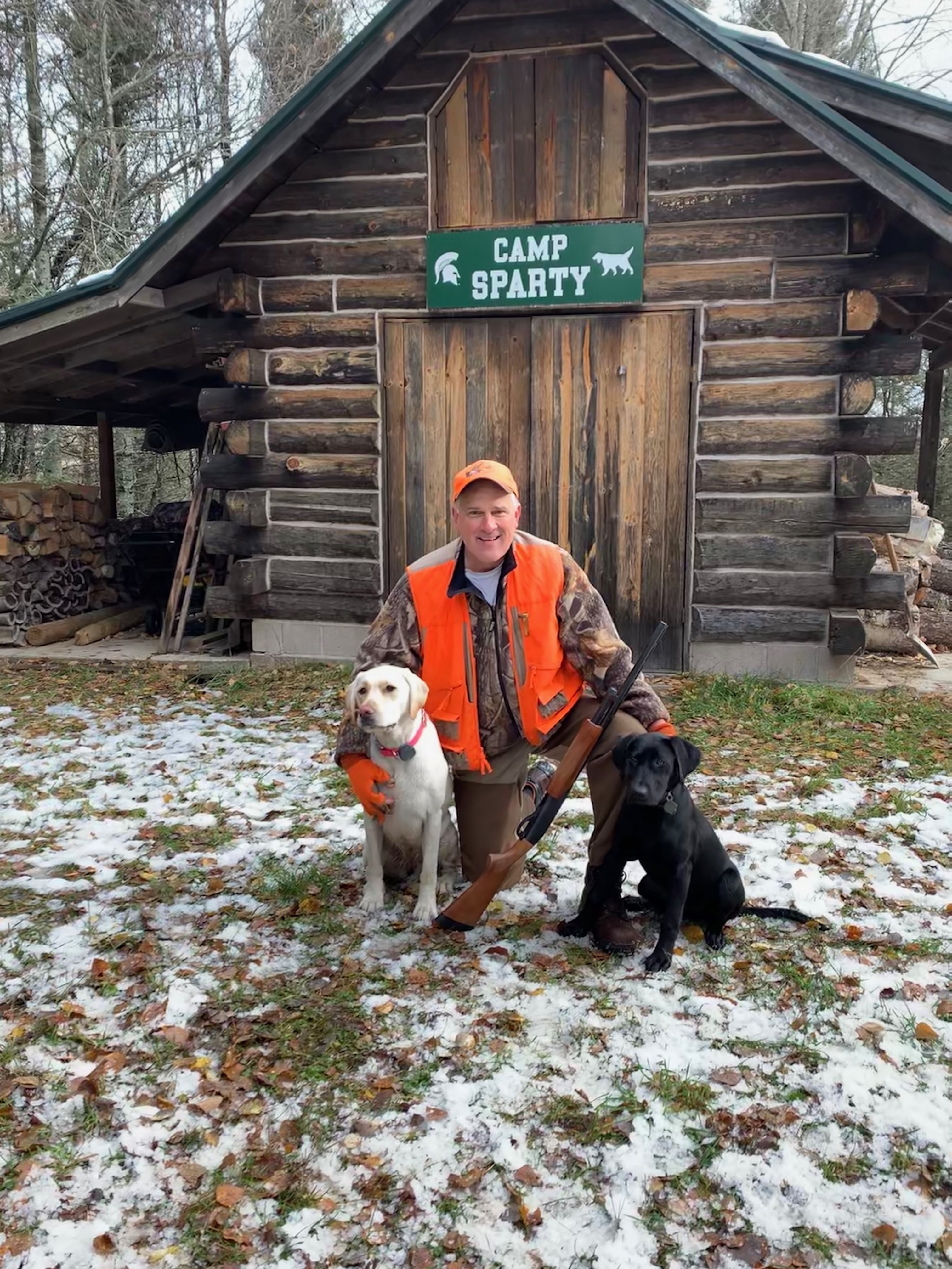 Dan Guyer and his two dogs in front of a cabin