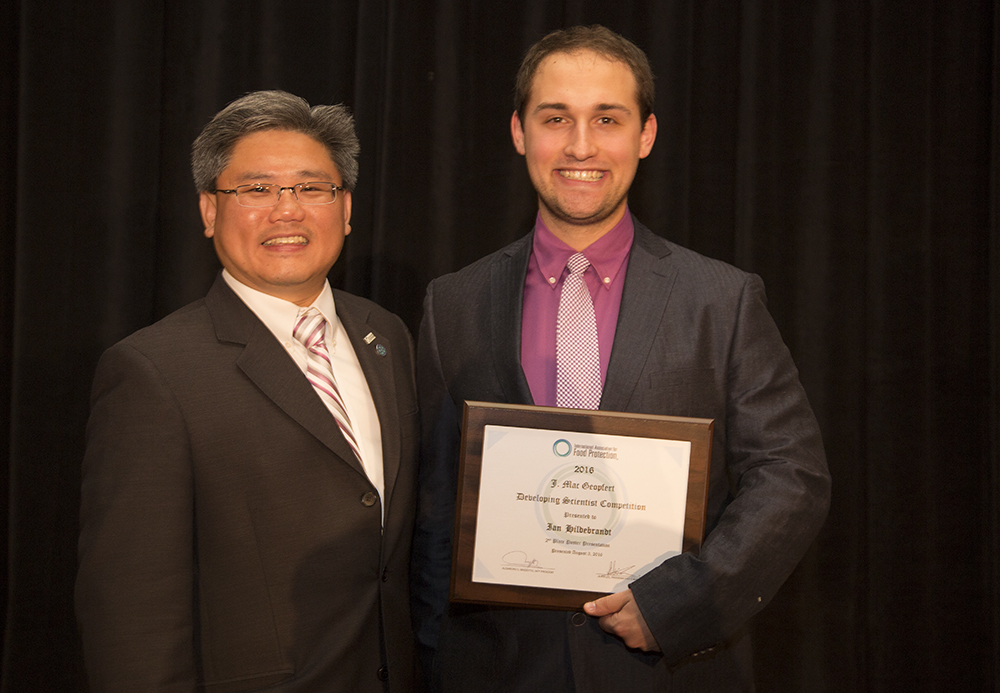 Photo of Ian Hildebrandt receiving 2nd-place in the developing scientist poster competition at IAFP 2016, presented by IAFP Program Chair-Elect, Dr. Alvin Lee.