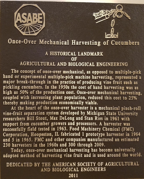 Photo of a historical landmark of Agricultural and Biological Engineering: Once-over mechanical harvesting of cucumbers.   The concept of once-over mechanical, as opposed to multiple-pick hand or experimental multiple-pick machine harvesting, represented a major break-through in the practice of producing vine fruit such as pickling cucumbers.  In the 1950's the cost of hand harvesting was as high as 50% of the production cost.   Once-over mechanical harvesting, coupled with increasing plant population, reduced this cost to 25% thereby making production economically viable.  At the heart of the once-over harvester is a mechanical pinch-roll vine-fruit separation system developed by Michigan State University researchers Bill Stout, Max DeLong and Stan Ries in 1961 with support from cucumber growers and processors.  A harvester was successfully field tested in 1963.   Food Machinery Chemical (FMC) Corporation, Hoopeston, IL fabricated 1 prototype harvester in 1964 and 5 in 1965.  FMC and other companies manufactured an estimated 230 harvesters in the 1960's and 300 through 2009.     Today, once-over mechanical harvesting has become universally adopted method of harvesting vine fruit and is used around the world.   Dedicated by the American Society of Agricultural and Biological Engineers, 2011. 