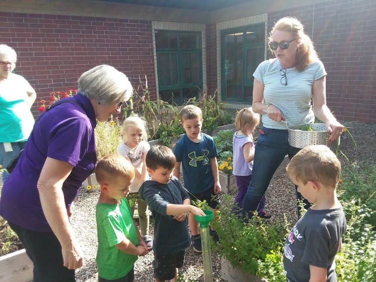 Students and Extension Master Gardeners examine a rain gauge