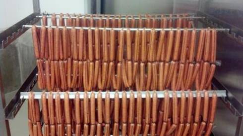 Smoked sausage drying on industrial racks.