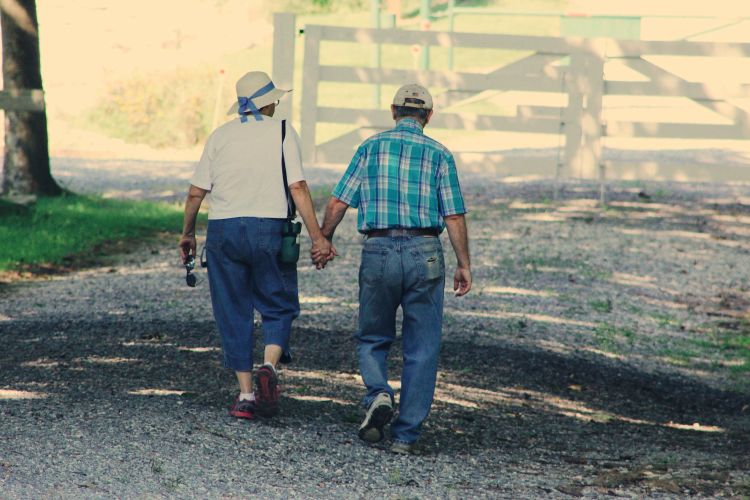 Two older people walking and holding hands.