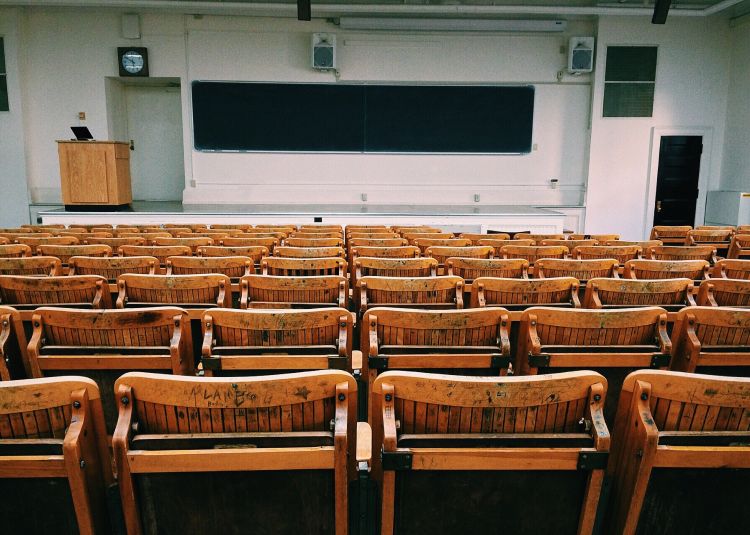 Wooden seats in auditorium with stage and podium at the front.