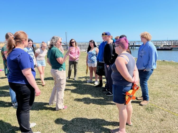 students standing around on the grass in front of the harbor talking with an MSU Extension staff member.