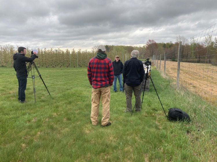 Photo of videographers conducting an interview in an apple orchard.