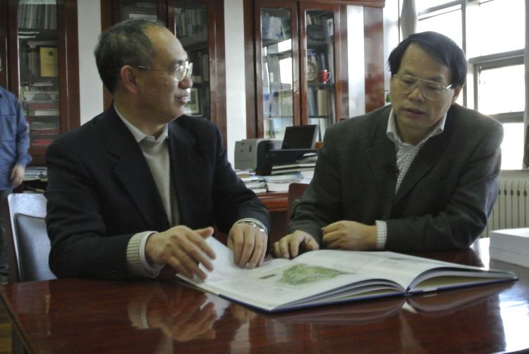 Zhiyun Ouyang and Jack Liu look over a book while talking