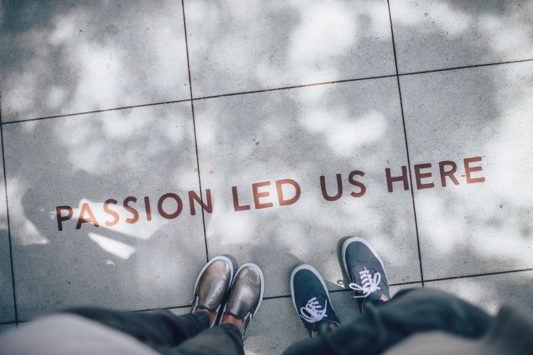 Feet on sidewalk next to the words Passion Led Us Here