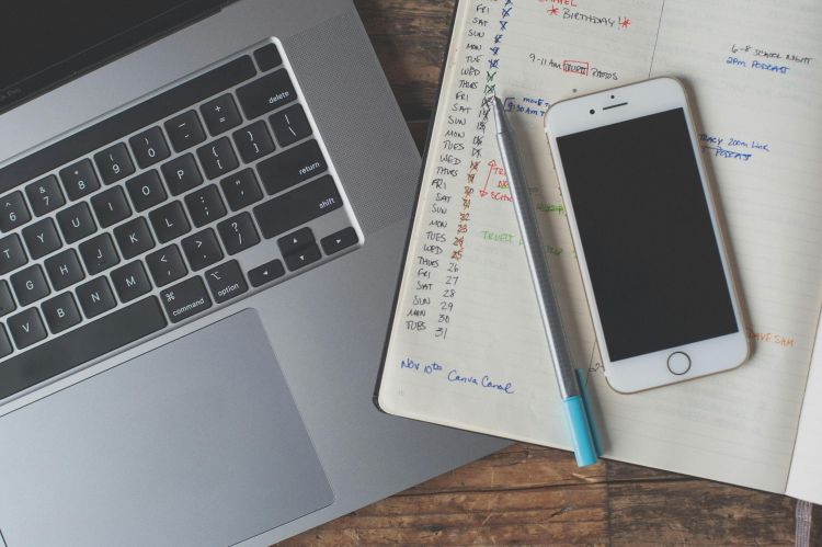 A laptop and cell phone on a notebook.