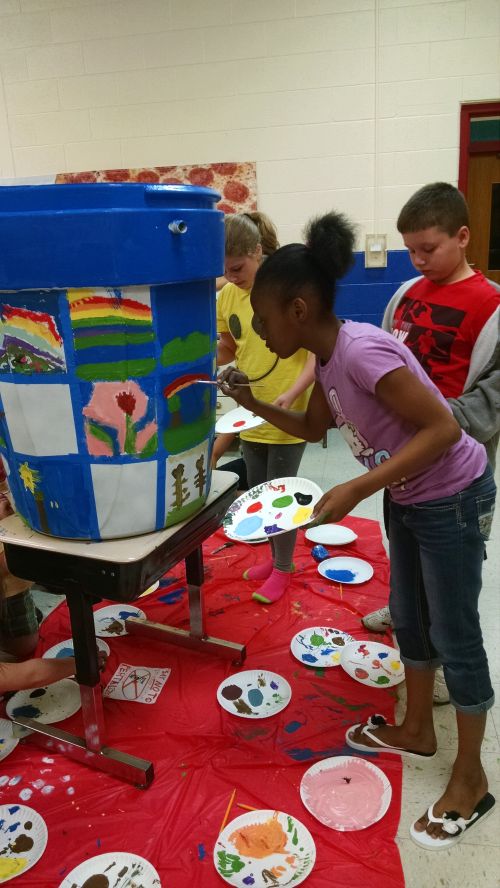 Bay County students paint rain barrels as part of an environmental art project.The barrels will be on display at various locations in Bay County during August. Photo: Katy Hintzen | Michigan Sea Grant