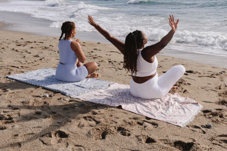 Two women doing yoga on a beach.