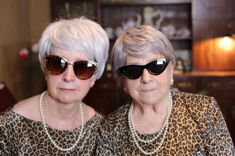 Two older women in sunglasses and matching clothes.