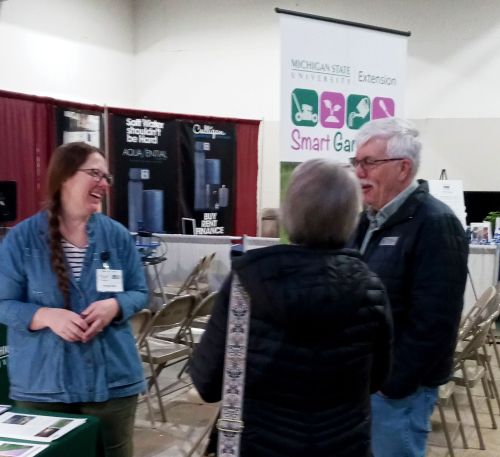 Three people stand and talk at a garden show.