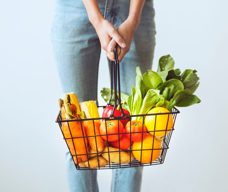 Woman holding basket of fresh vegetables.