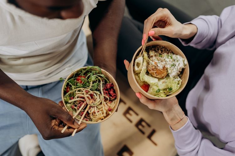 Two people eating bowls of healthy food.