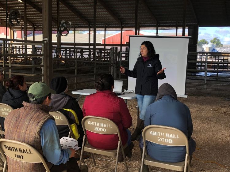 Dairy educator speaks to small group in dairy exhibition hall.