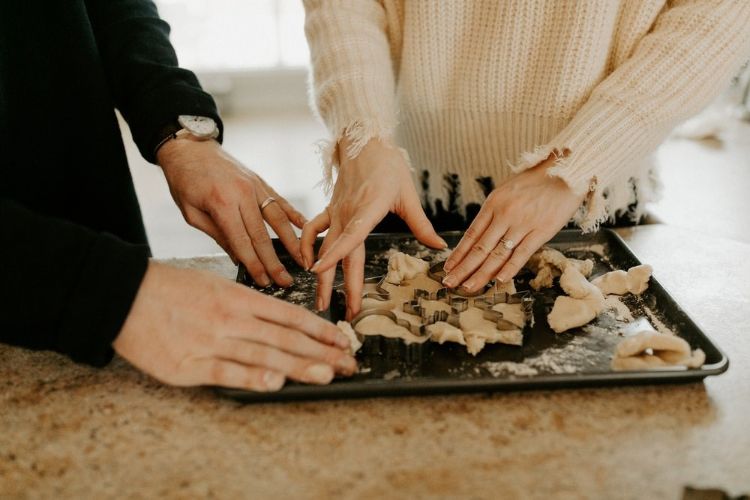A closeup image of two people's hands kneading dough.