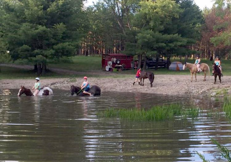 Riders on horseback crossing a body of water.