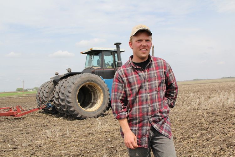 A farmer smiling in front of his tractor