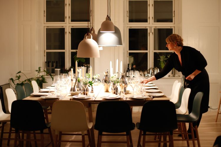 Woman in black dress setting table for holiday dinner.